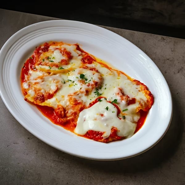 La Bella Luna's baked lasagna, topped with melted mozzarella cheese and fresh parsley, in a white dish.