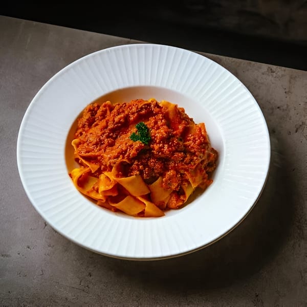 La Bella Luna's pappardelle pasta with rich bolognese sauce, garnished with a sprig of parsley.