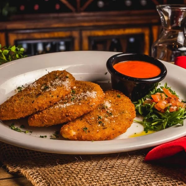 Three breaded mozzarella sticks with marinara sauce and a side salad on a white plate.