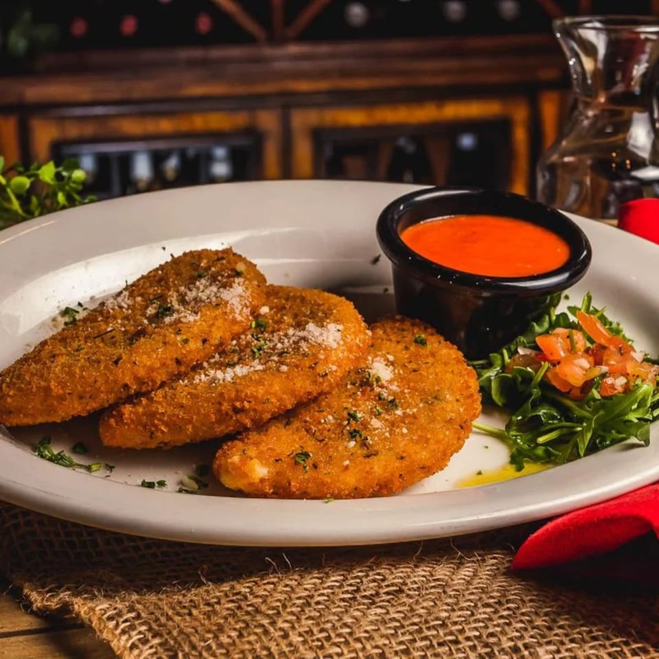 Three breaded mozzarella sticks with marinara sauce and a side salad on a white plate.